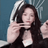 a girl with long hair is holding a pair of chopsticks in her hand