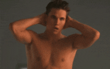 a shirtless man with his hands on his head