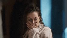 a woman covering her mouth with her hand while wearing a bathrobe