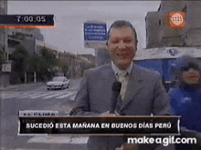 a man in a suit and tie is standing in front of a microphone on a news channel .
