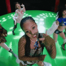 a group of young women are dancing on a green stage