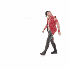 a wrestler in a red vest and black pants is standing in front of a white background .