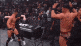 two men in wrestling trunks are standing next to each other in front of a crowd in a stadium .