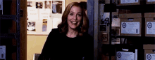 a woman is smiling while standing in a room with boxes on the shelves .