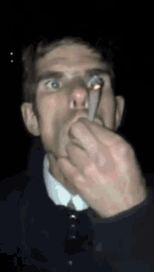 a man is smoking a cigarette with his hand on his nose