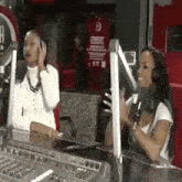two women are talking into microphones in a radio studio .