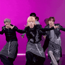 a group of young men are dancing in front of a purple background and one of them is wearing a black shirt with the number 1 on it
