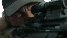 a man in a hat looking through a rifle scope