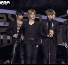 a group of young men are standing in front of a microphone holding awards .