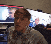 a man sitting in front of a computer screen with a bottle of coke in front of him