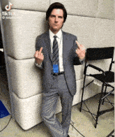 a man in a suit and tie giving the middle finger in front of a chair