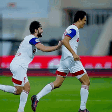 two soccer players are running on a field and one has the number 8 on his jersey