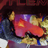 a man and woman are shaking hands in front of a sign that says tiffany