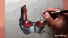 a person is drawing an ant man helmet with a brush on a piece of paper