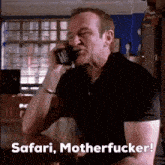 a man sitting at a table talking on a cell phone with the words safari motherfucker below him