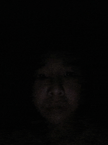 a person 's face is shown in the dark with their eyes closed