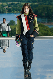 a model walks down a runway wearing a military jacket