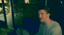 a young man is sitting on a couch in a dark room with a bicycle in the background .