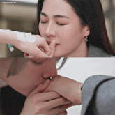 a woman kissing another woman 's hand with a lingosmgifs watermark at the bottom