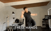 a man is dancing in a room with the words `` these hands '' written on the bottom .