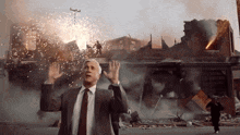 a man in a suit and tie is standing in front of a building that is on fire
