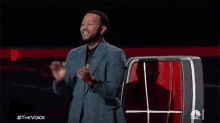 a man in a suit is standing on a stage with his arms outstretched and screaming .
