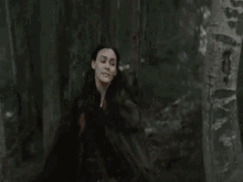 a woman is running through a forest while holding a horse .