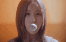 a close up of a woman blowing a bubble with a condom in her mouth .