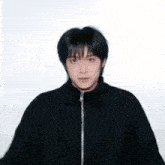 a young man wearing a black jacket with a zipper on the front