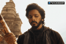 a man with a beard is holding a stick in front of a temple and a twitter logo that says wickreddy