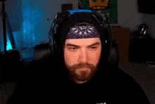 a man with a beard wearing headphones and a bandana is making a funny face .