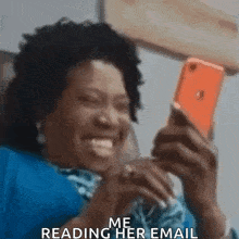 a woman is laughing while looking at her phone and says `` me reading her email '' .