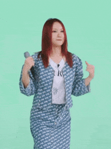 a woman with red hair is holding a microphone while wearing a blue jacket and skirt .