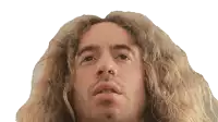 a man with long curly hair and a nose ring looks at the camera