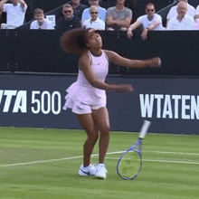 a woman is holding a tennis racquet on a tennis court in front of a banner that says wta 500