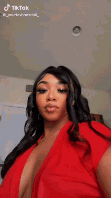 a woman in a red dress is taking a selfie in a room .