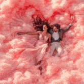 a man and a woman are laying in pink clouds holding glasses of wine