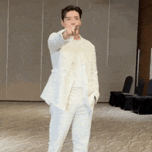 a man in a white suit is pointing his finger