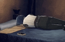 a person is laying on a bed with a book on the floor .