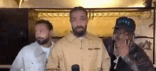 three men are standing next to each other in a room .