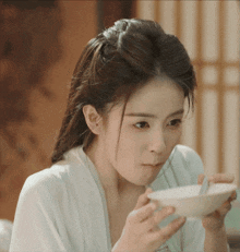a woman in a white robe is eating a bowl of food