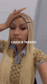 a woman with long blonde hair is taking a selfie with the words cardi b tanked on the bottom