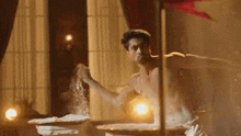 a shirtless man is standing in front of a table spreading flour on it .