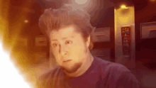 a man in a purple shirt is looking at something with a can of flex glue in the background .
