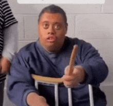 a man with down syndrome is sitting in a chair and holding a stick .
