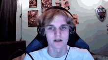 a young man wearing headphones is sitting in front of a wall with posters and a shield that says link