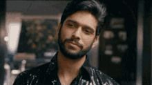 a man with a beard is wearing a black sequined shirt and smiling
