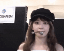 a woman wearing a hat with a microphone in her mouth is standing in front of a sign that says serafim .