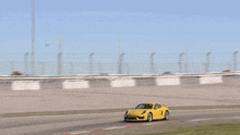 a yellow sports car is driving down a track