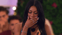 a woman is covering her mouth with her hand while wearing a bracelet and rings